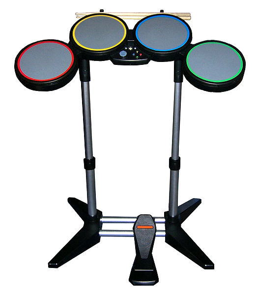 The drum controller, which features 4 pads, a bass drum pedal, and real drumsticks. The Wii version features white drums.