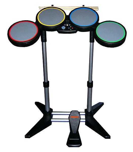 The drum controller, which features 4 pads, a bass drum pedal, and real drumsticks. The Wii version features white drums.